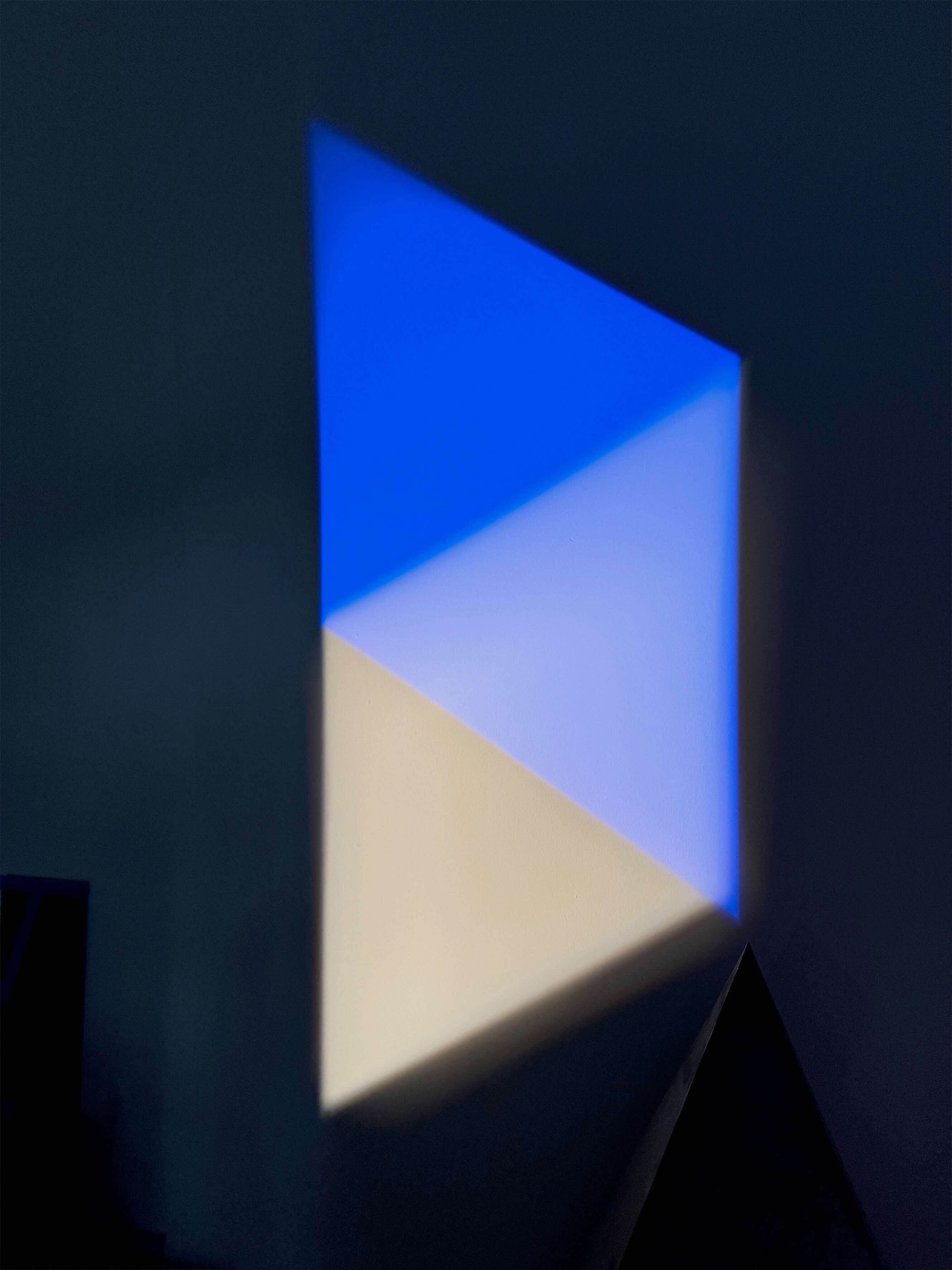 Illumination of a trapezoid divided into triangles of royal blue, powder blue, and grey on a black background