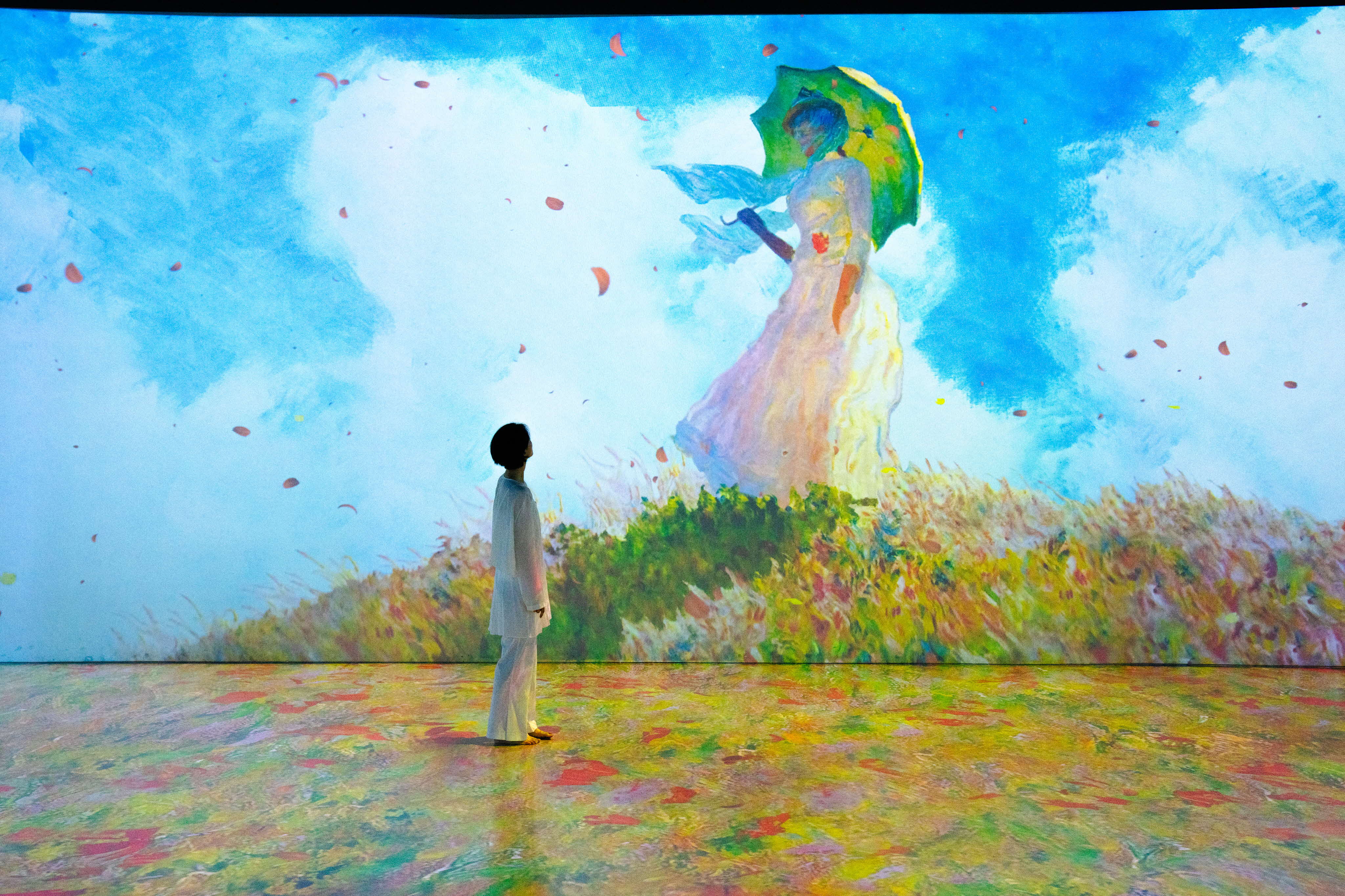 Painting of floating figure in the sky with umbrella and a person looking up in a field of colors. Painting by Monet.