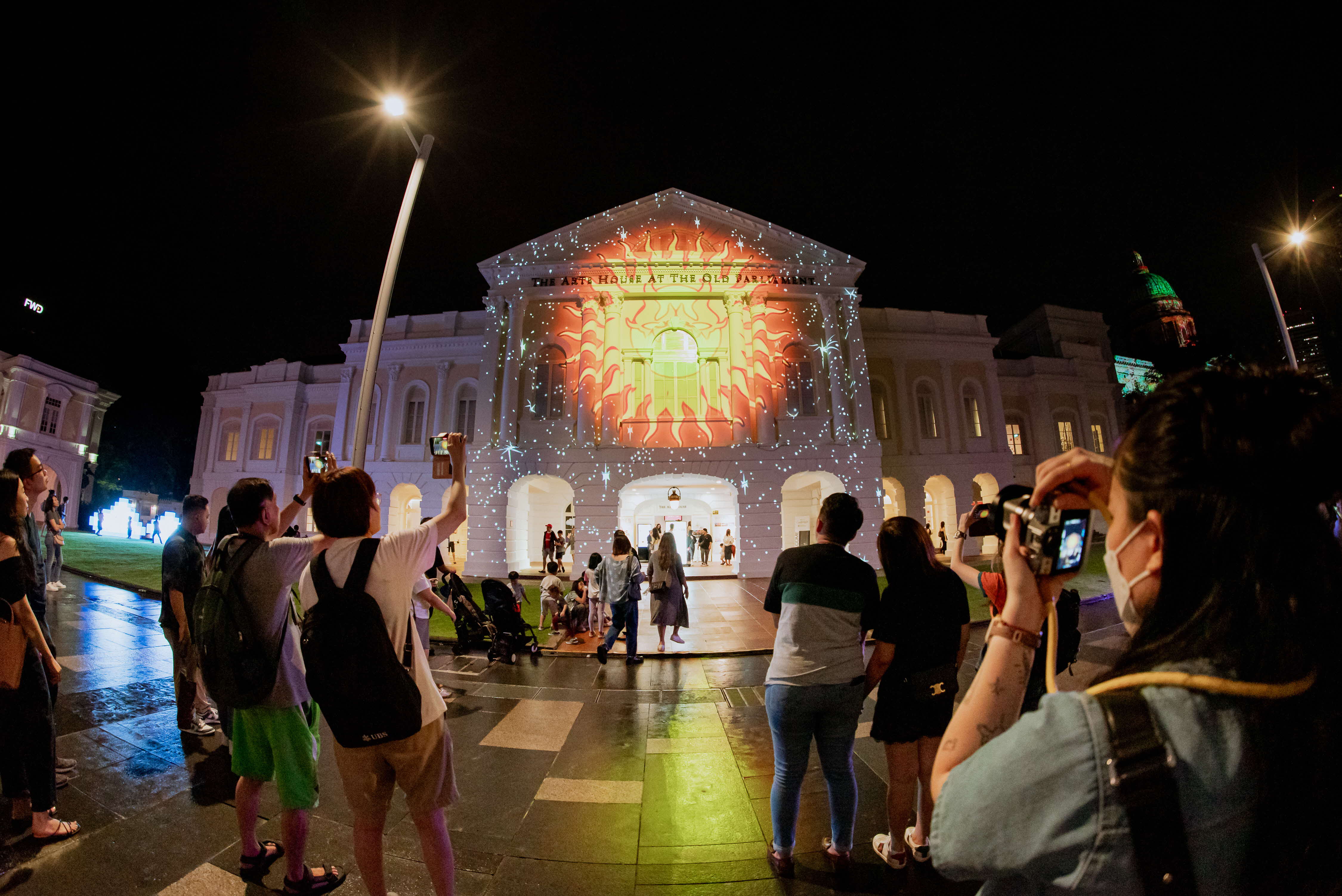 Photo of a crowd taking pictures of the projection on The Arts House facade