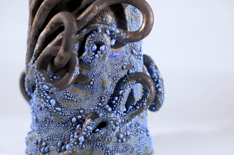 Close up of artwork which has long tentacle-like attachments and blue dots painted in different sizes