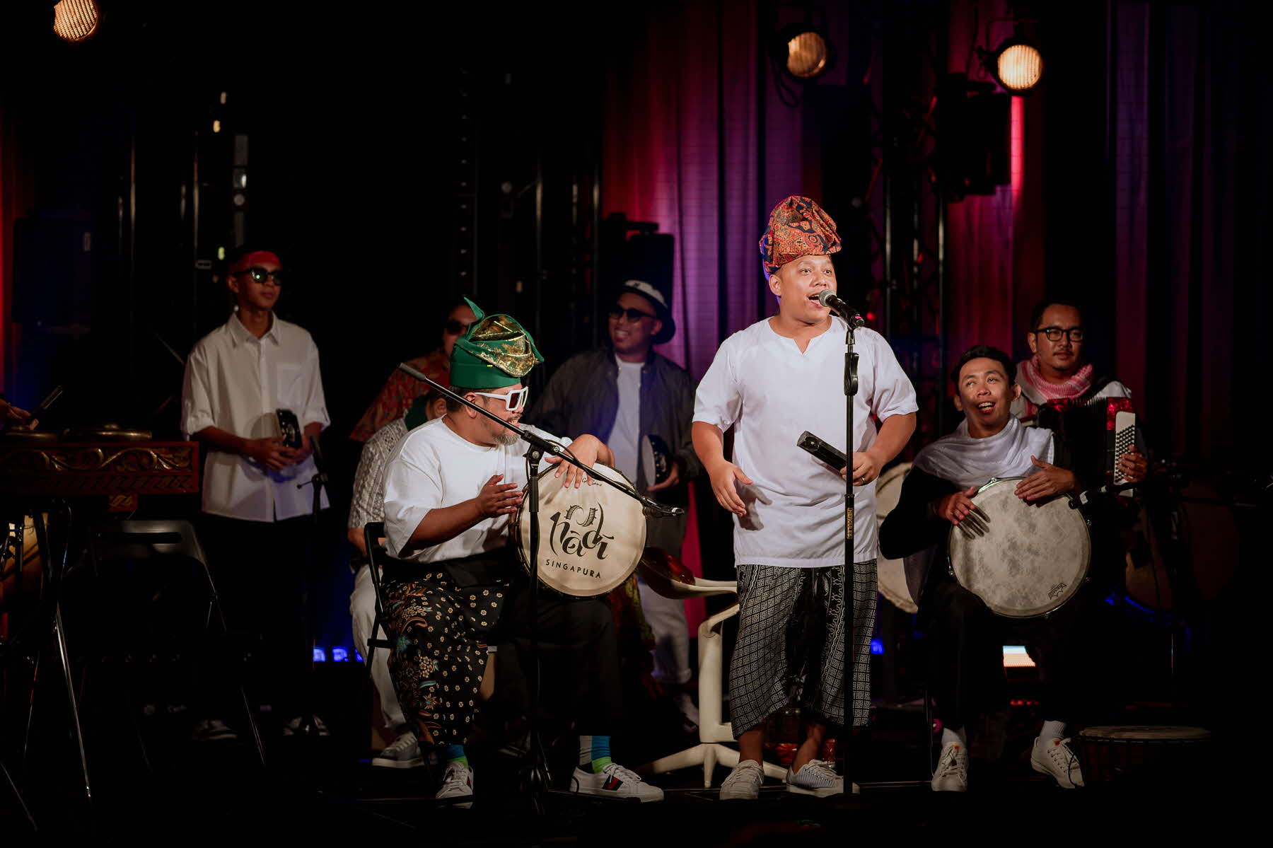 Image of a folk band playing instruments and singing against a dark backdrop