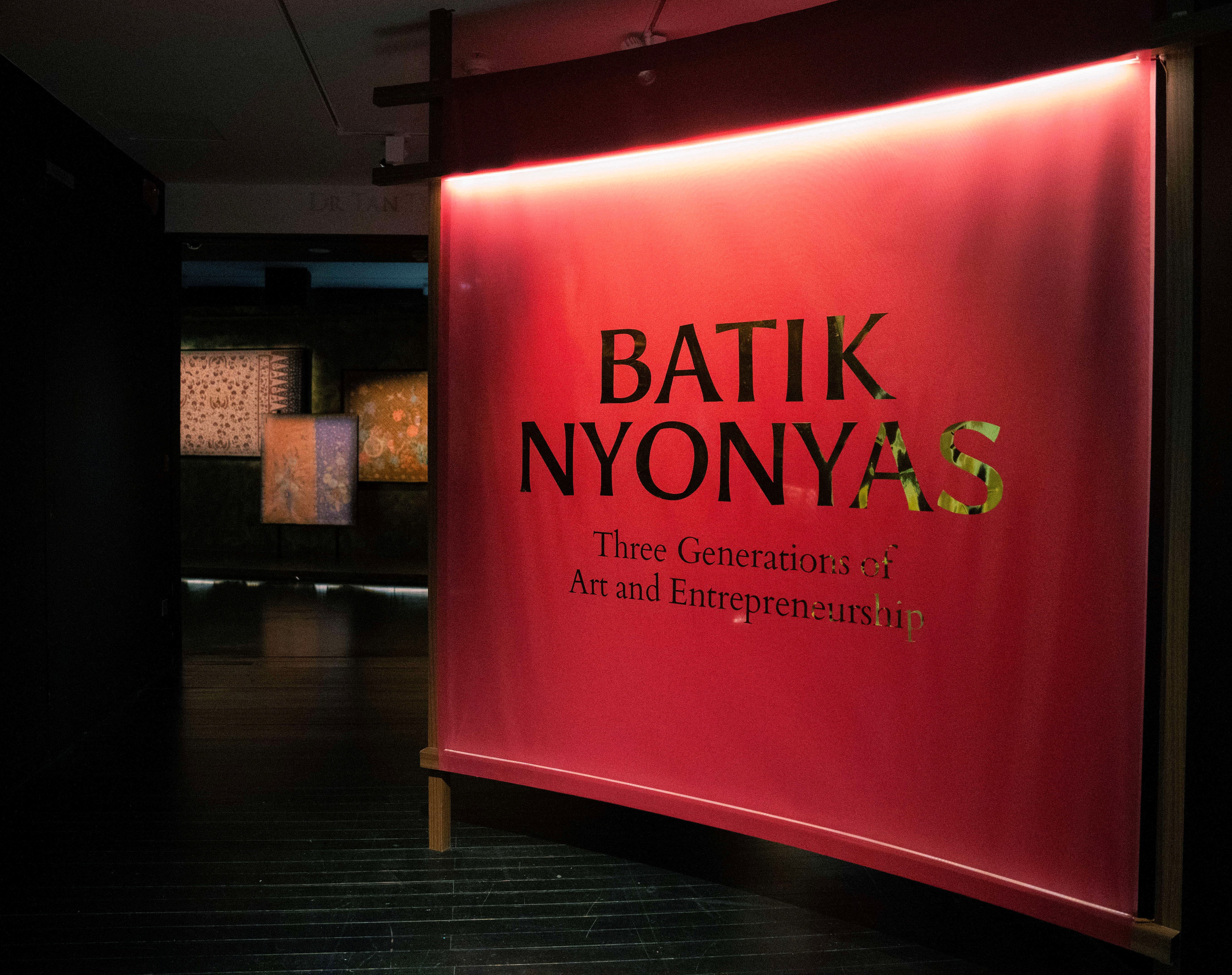 Image of the entrance to Batik Nyonyas exhibition illuminated in red and gold text