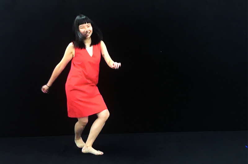 Image of a woman in a red dress with her hair down in the middle of a dance move on a plain black background