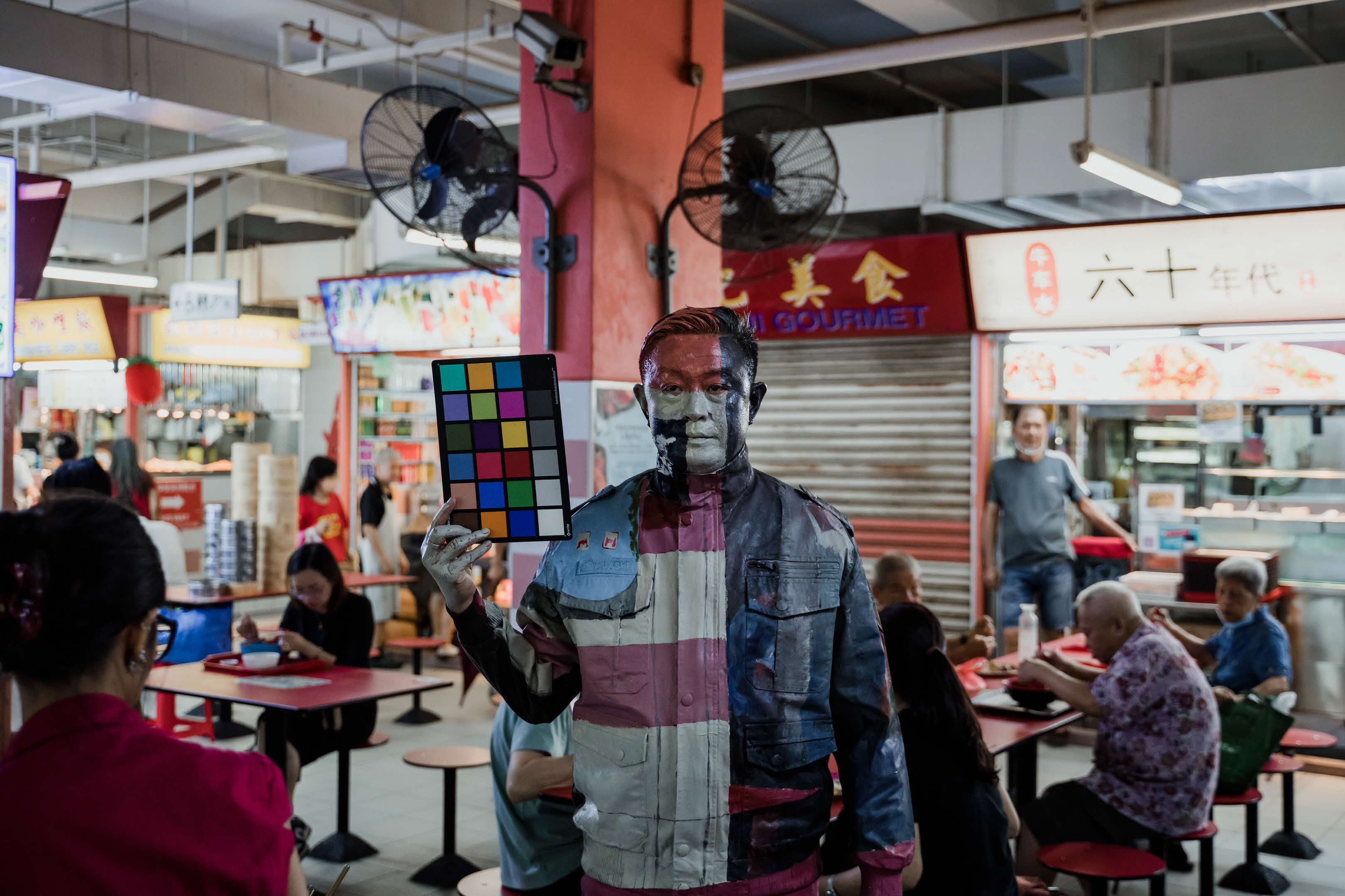 Close up image of person painted to blend in with Chinatown Complex Food Centre