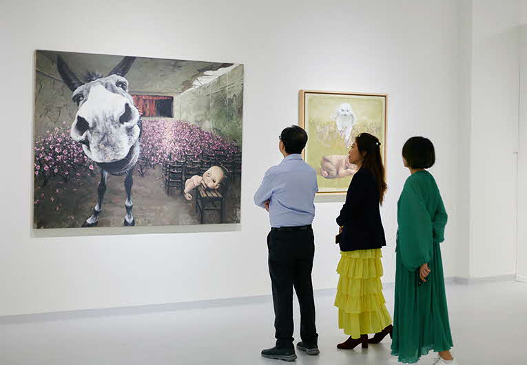 Image of people in a white gallery space looking at a large artwork on the wall