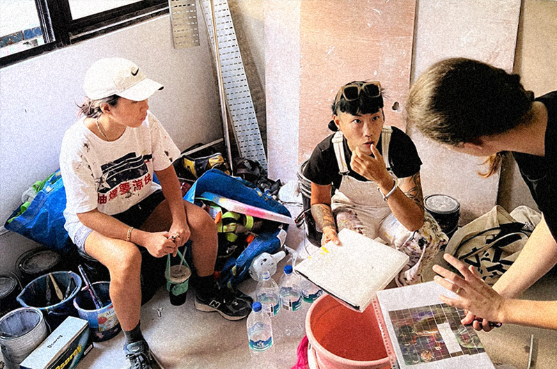 Image of three people discussing avidly surrounded by art materials