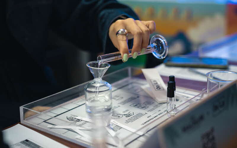 Close up of a person pouring liquid from a test tube into a pitcher