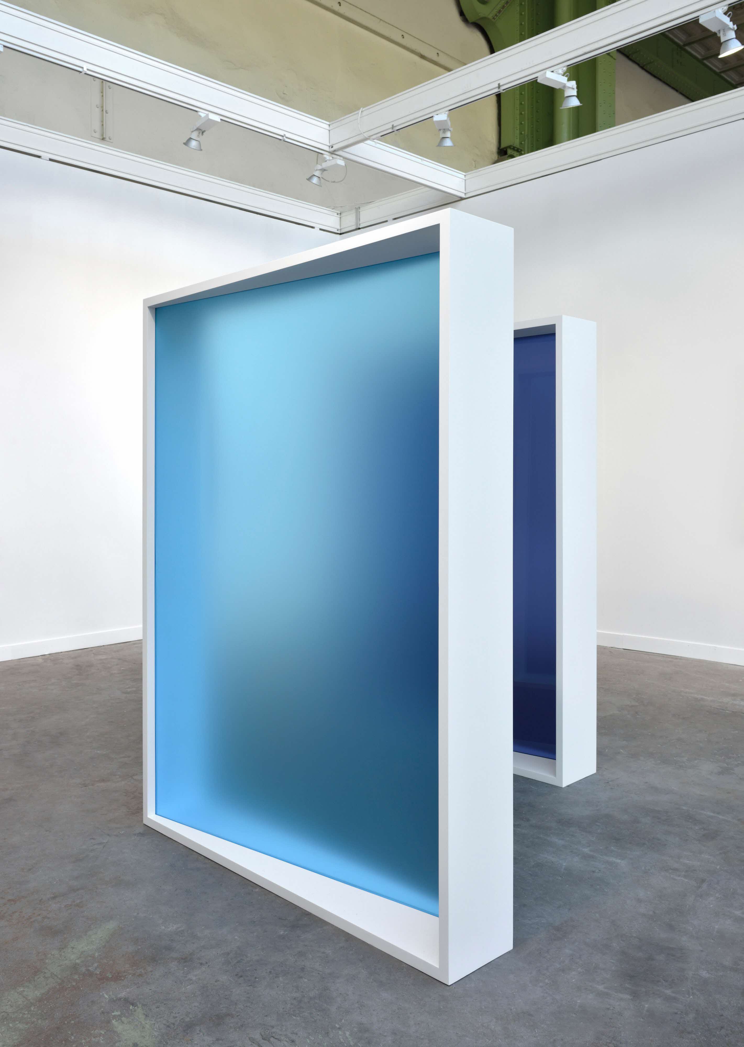 A minimal white studio space with two white frames facing diagonally, with blue frosted glass inserts