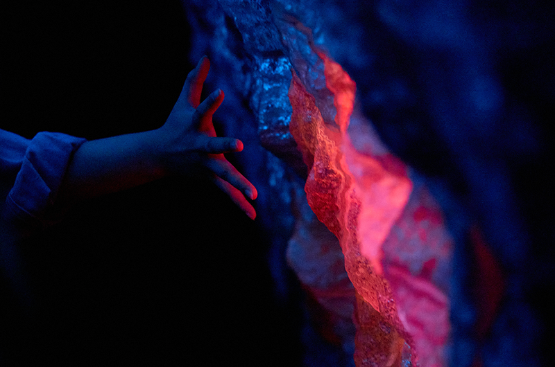 Image of hand reaching out to hold a glowing magenta ember