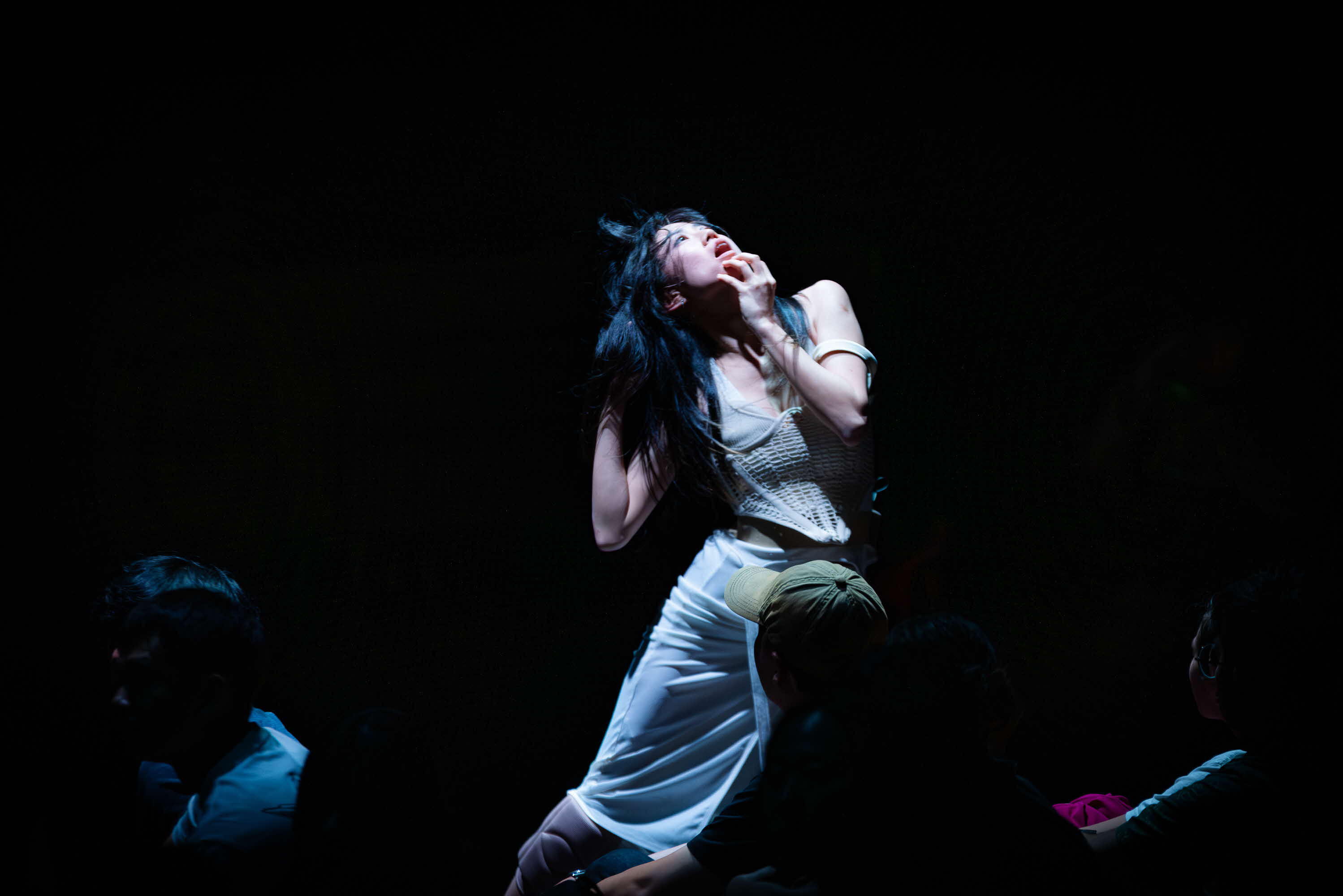 Image of contemporary dancer against a dark background looking up