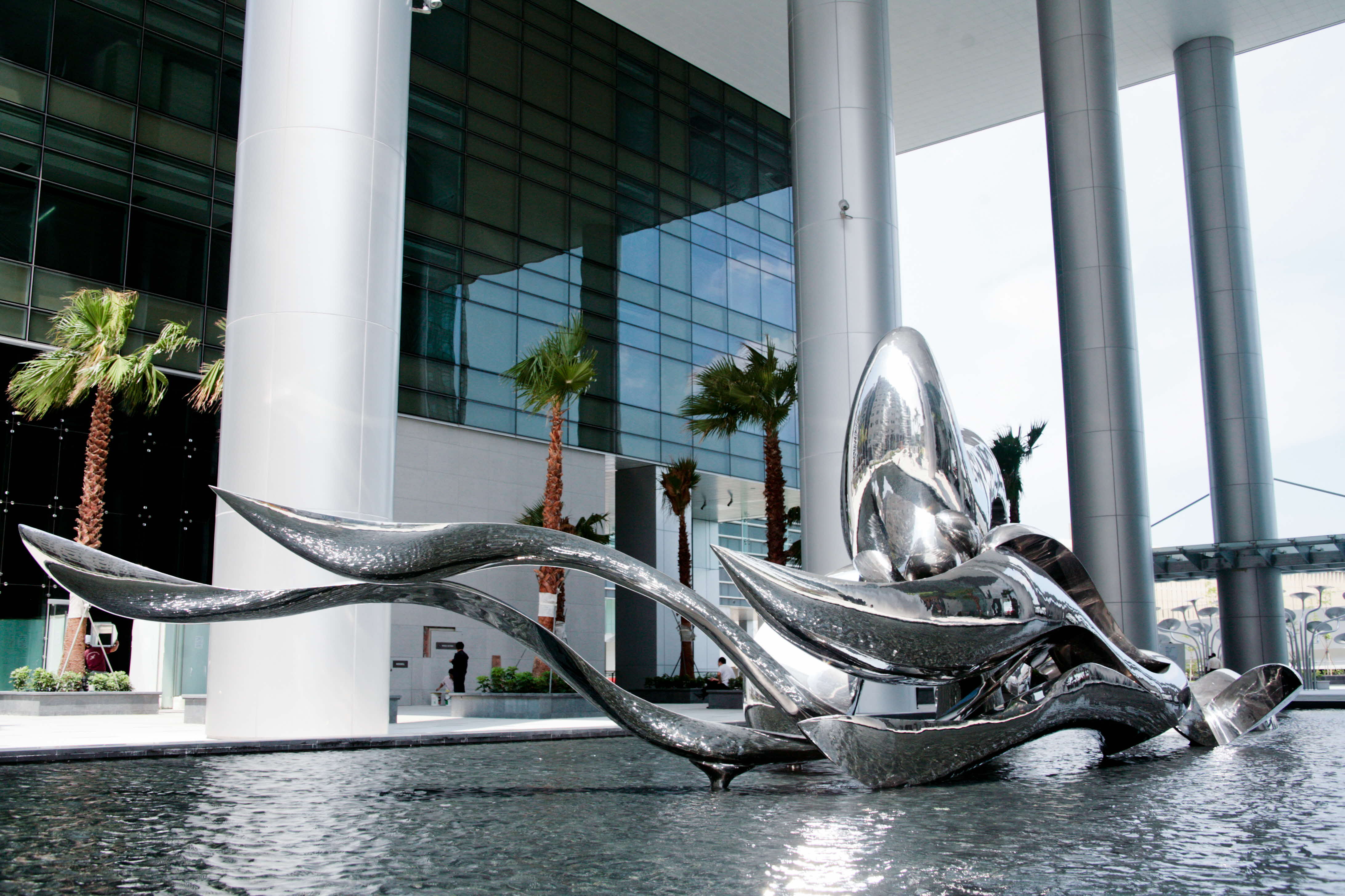 Image of wave metal sculpture on top of a water installation outside a building