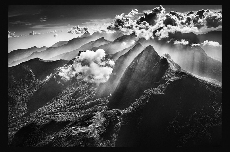 Black and white image of a glowy hazy mountaintop surrounded by clouds