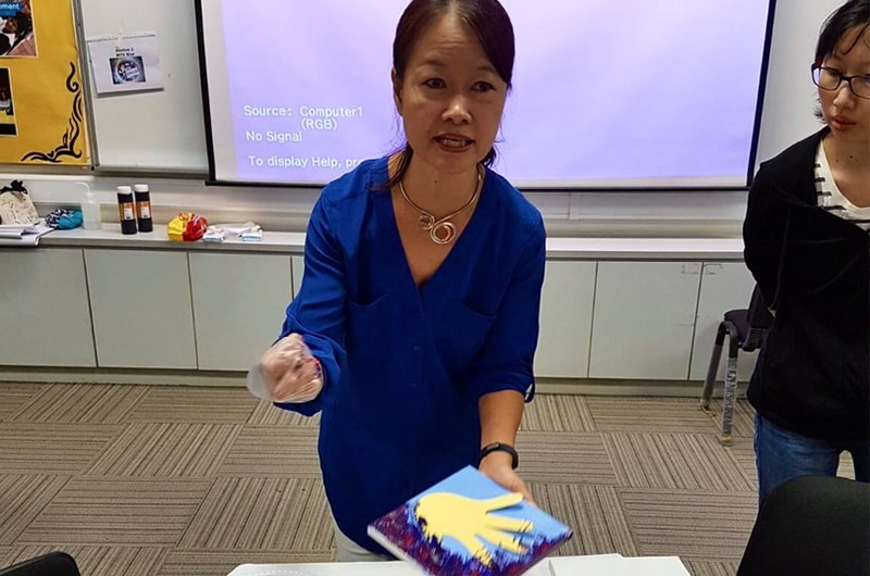 Image of woman in blue shirt showing her glass art