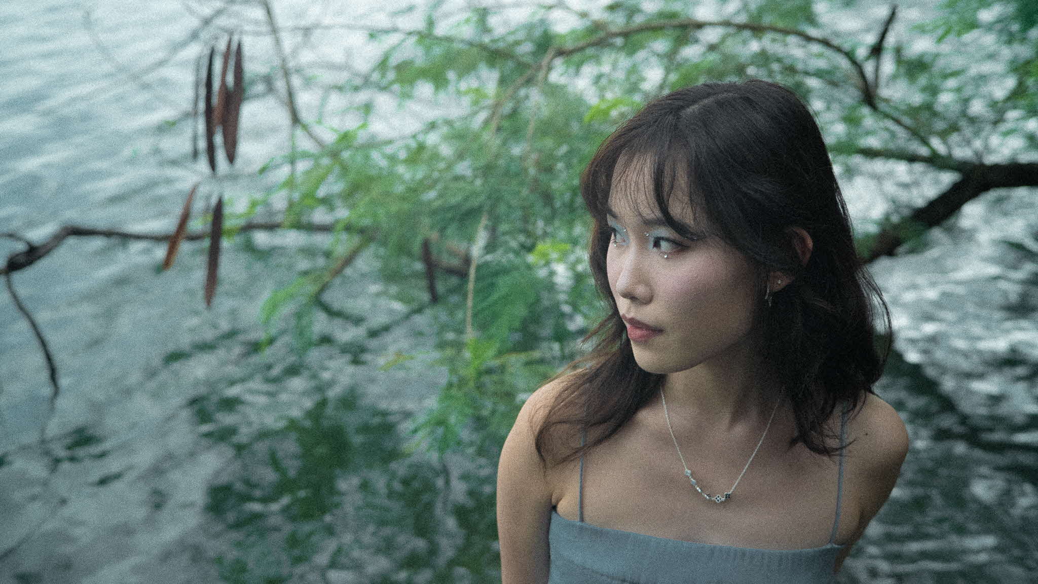 Young woman standing in front of a tree looking sideways