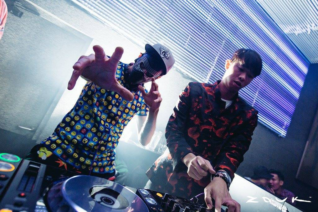 2 men performing as DJs in a club